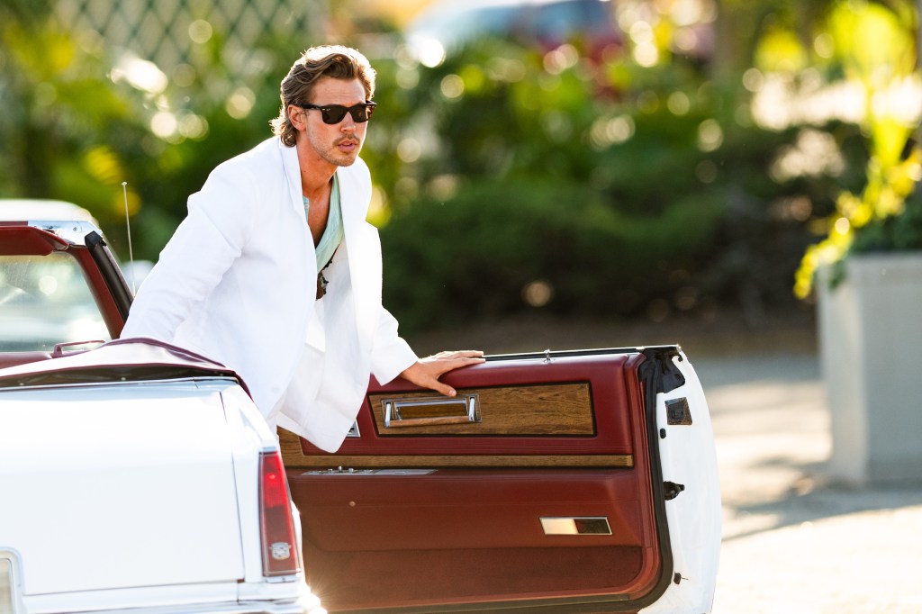 Austin Butler on the set of the "Miami Vice" reboot as detective James “Sonny” Crockett, wearing a white suit and getting out of a white convertible.