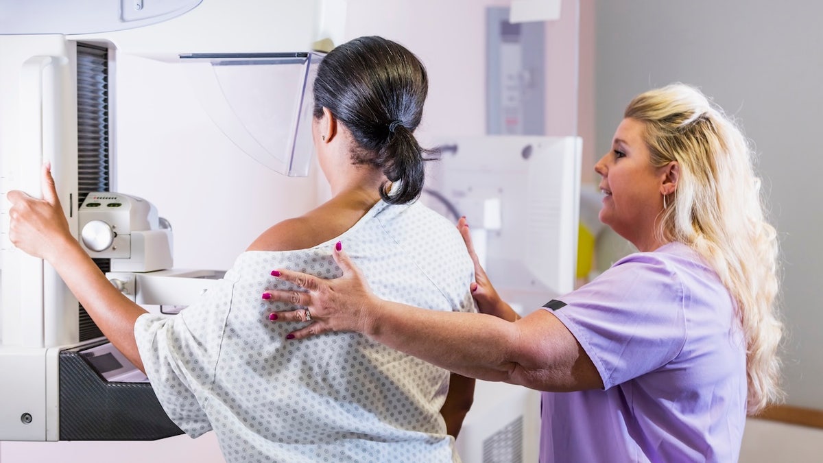 Woman getting mammogram with radiologist