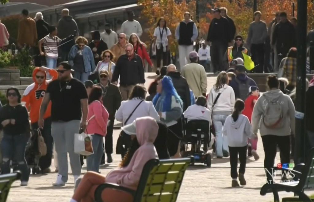 A large crowd of people walking along a boardwalk.