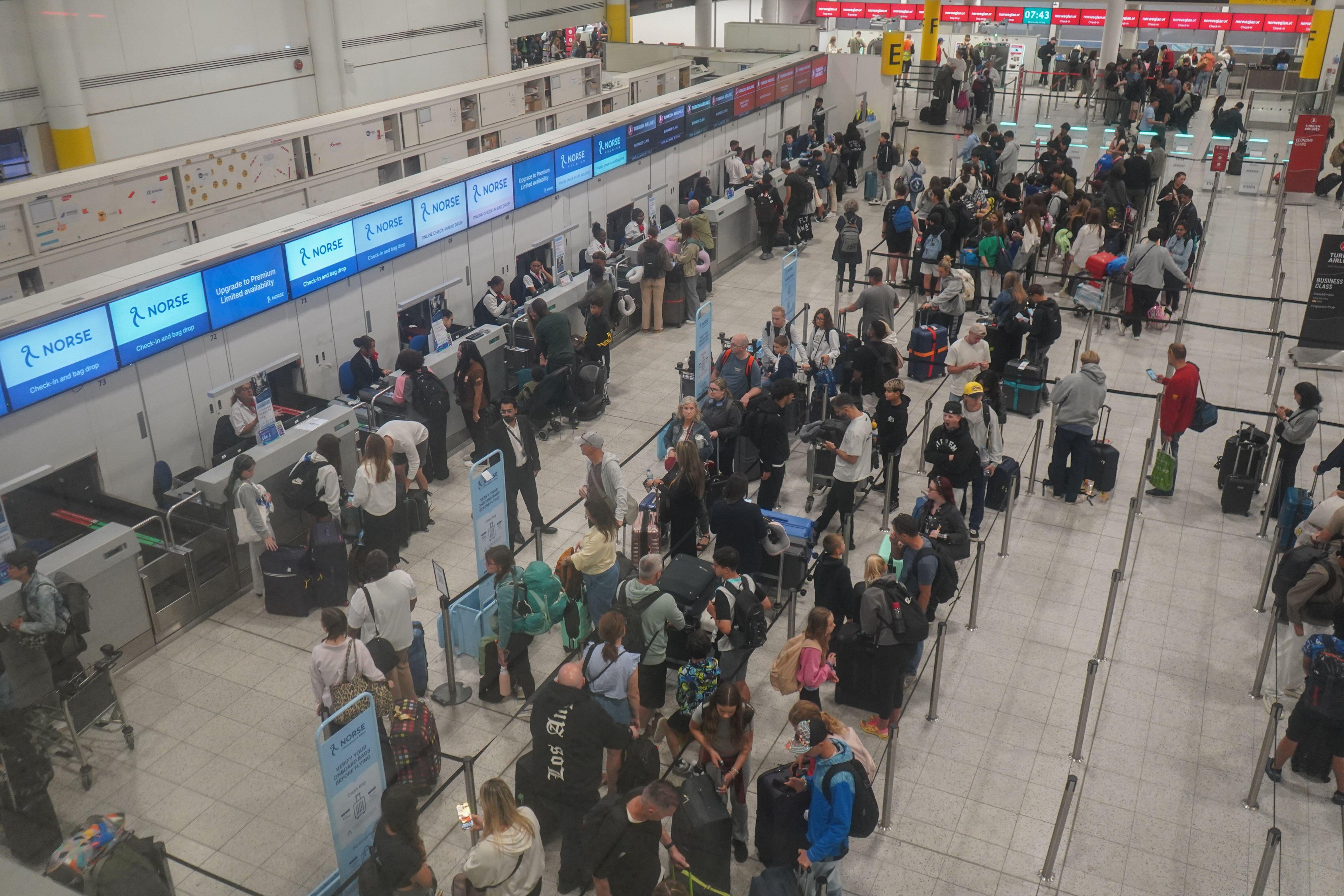 Busy Gatwick airport check-in area with many travelers.