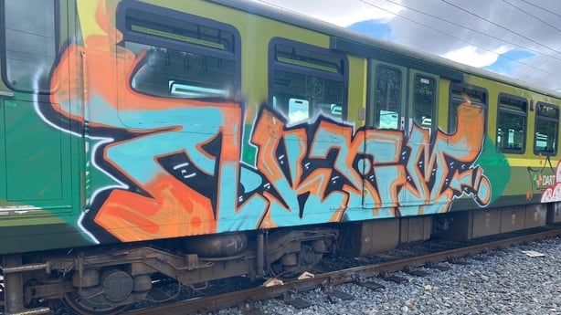 a train with graffiti on the side against cloudy sky