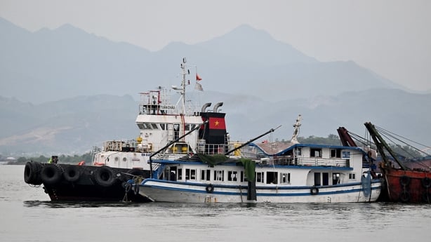 The tourist boat (C) that capsized is towed back to the port in Ha Long bay, Quang Ninh p
