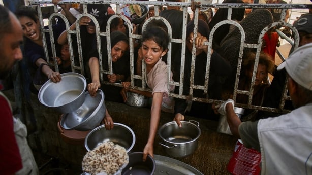 Palestinians queue to receive a hot meal at a charity kitchen 