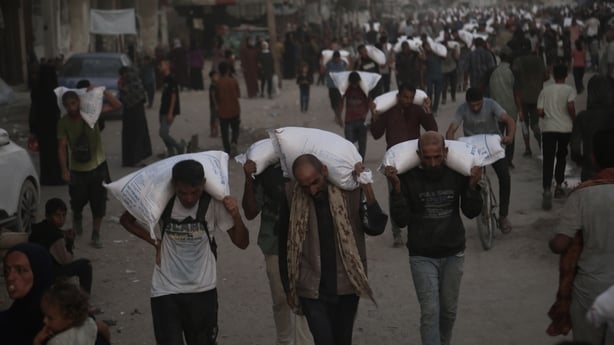  Palestinians receive bags of flour after waiting at a distribution point