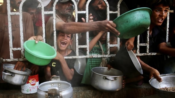 People crowd against a metal fence trying to get food at a charity kitchen in the Mawasi area of Khan Younis in southern Gaza