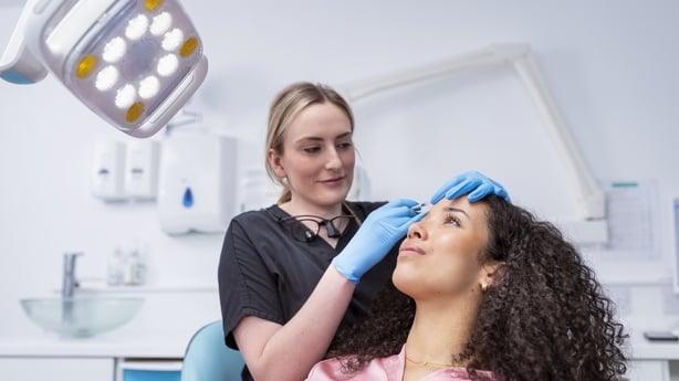 Cosmetic nurse injecting botox into patient in dental surgery