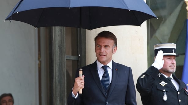 French President Emmanuel Macron stands in the rain on the steps of the Elysee Palace in Paris, France
