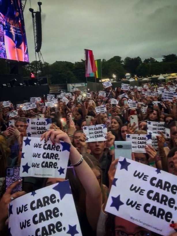 Image shows Olivia Rodrigo fans holding up signs that say 