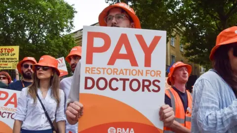 Getty Images Doctors on a picket line during a previous strike. They are carrying orange BMA banners and wearing orange BMA sunhats