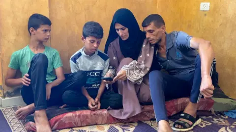 Iman al-Nouri (2nd right), her husband Hatim (right) and two of their sons look at photos on a mobile phone
