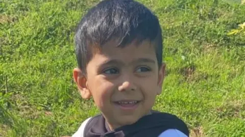 Family handout/PA MEDIA A young boy with short brown hair smiles as he looks away from the camera