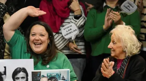 Reuters Adriana Metz (left) and Estela de Carlotto, president of the human rights organization Grandmothers of Plaza de Mayo, wave and clap during a news  conference announcing that Metz's brother has been found.