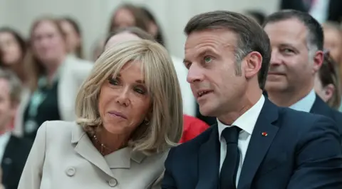 EPA Brigitte and Emmanuel Macron pictured at a public event in London earlier this month, seated and leaning towards each other