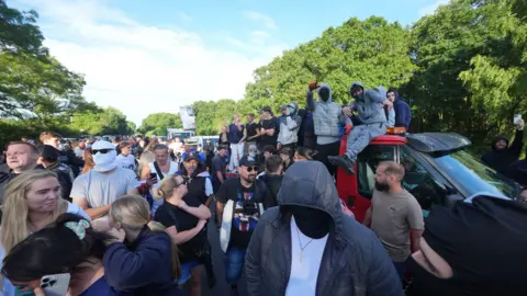 PA Media crowd of people - some wearing masks - gathering 