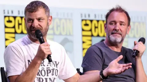 Getty Images Matt Stone and Trey Parker in casual clothes sitting in chairs, holding microphones