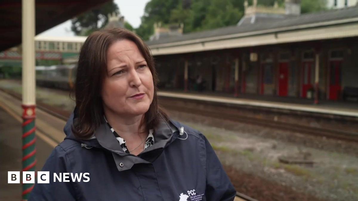 A picture of Alison Hernandez standing at a train station. She is wearing a black coat and has brown hair.