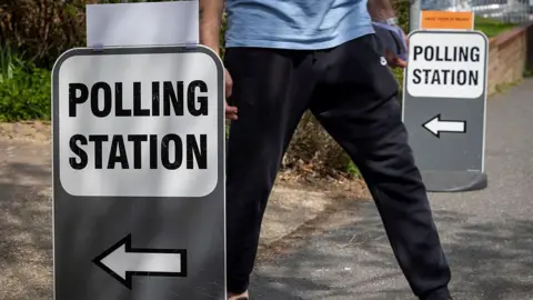 Getty Images A person in black trousers leaves a polling station. He walks past a sign saying polling station with an arrow.