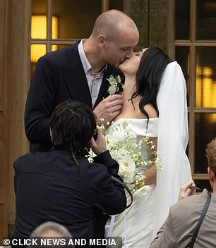 Meanwhile George wore a dark double breasted suit over a light open collared shirt with a flower, that matched his wife's bouquet, in his button hole
