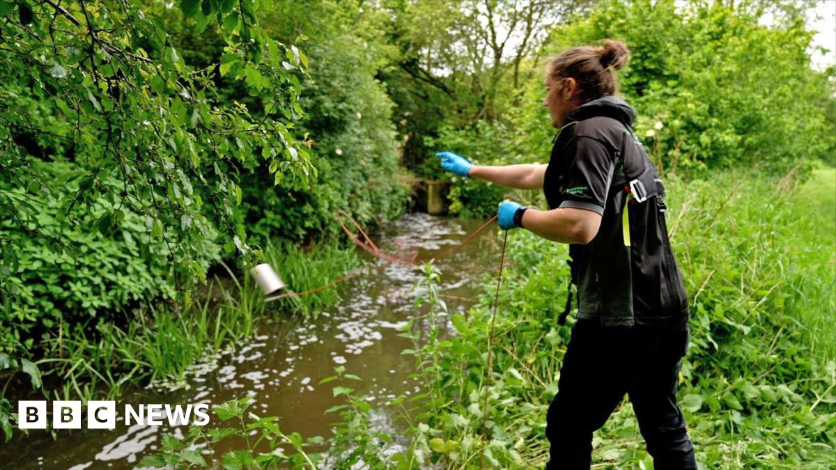 A man clad in a white jacket and wearing glasses conducts water testing at the Starcross laboratory in Devon.