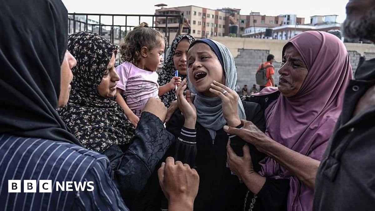 A group of women comfort another woman in the middle of their group in Khan Yunis.
