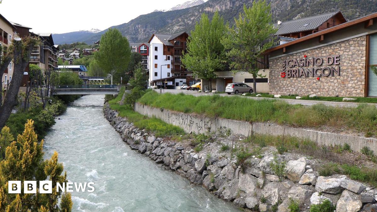 The river Guisane cuts through the French commune of Briançon. On one back a casino can be seen, in the background the Alps rise to the sky.