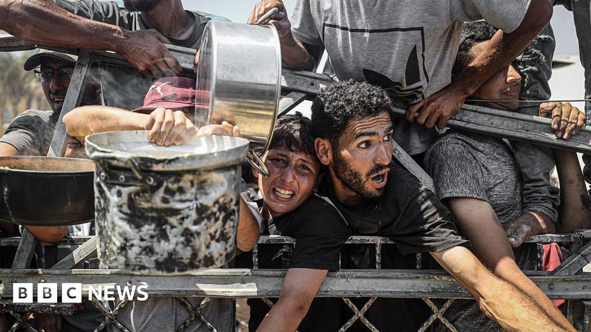 Palestinians carrying pans gather to receive hot meals from a charity kitchen in Gaza City, northern Gaza (23 July 2025)