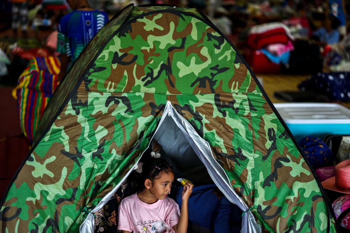 A young girl is shown inside a hut-like structure.