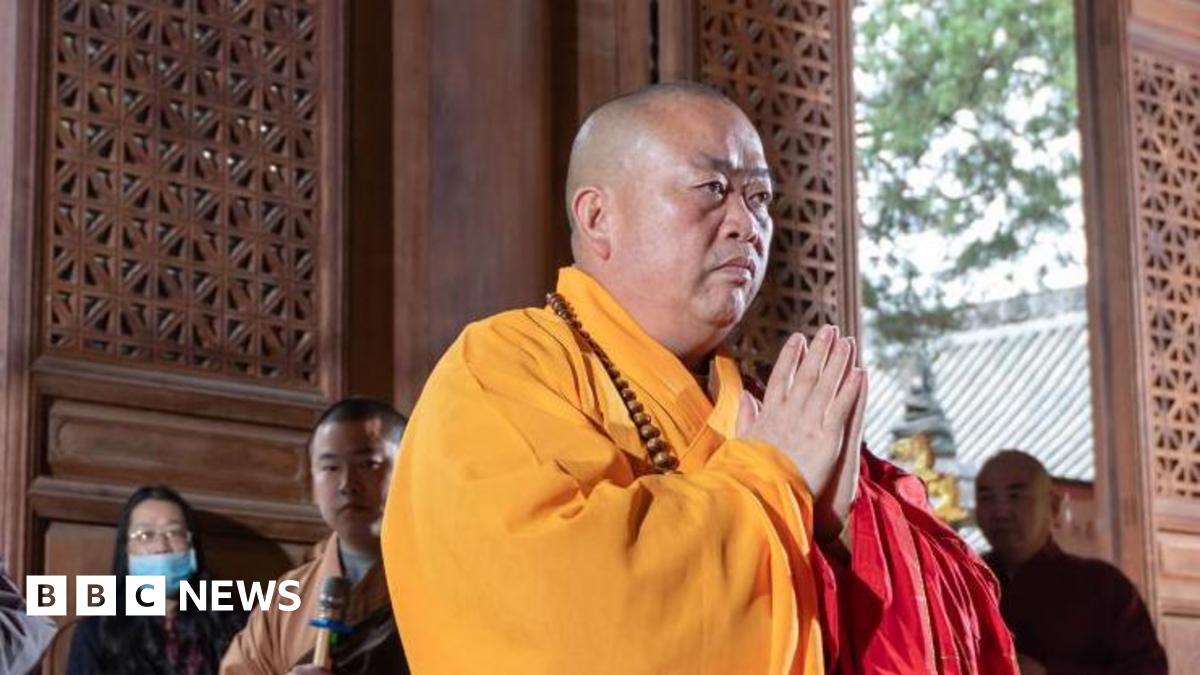 Shi Yongxin putting his palms together in a prayer position. He is wearing a yellow robe.