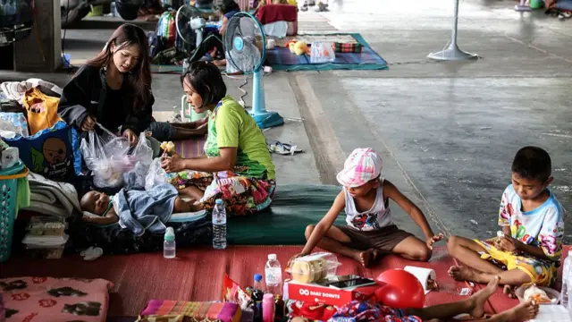 People evacuated from border areas sit on mats at an evacuation center at IQ New Town market amid the escalating conflict between Thailand and Cambodia in Surin, Thailand