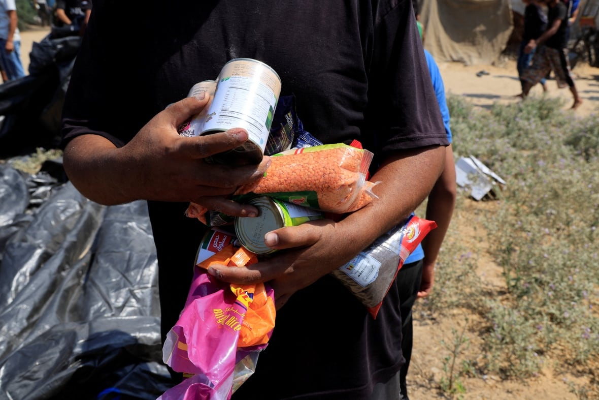 A man holds multiple food items.