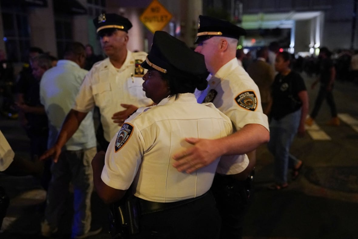 NYPD officers embrace each other.
