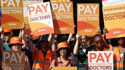 EPA Image shows doctors on strike holding placards outside St. Thomas's hospital in London on 25 July 2025