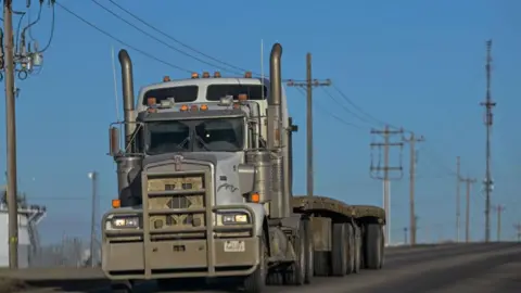 Getty Images A truck drives along a backroad, with electric poles and wires stretching across the landscape in Edmonton, Alberta