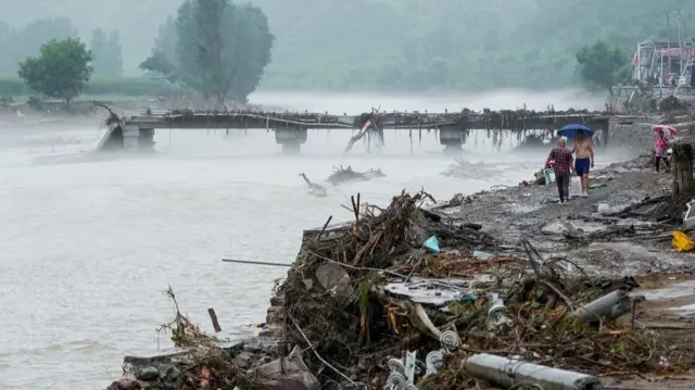People walking among debris along a river bank
