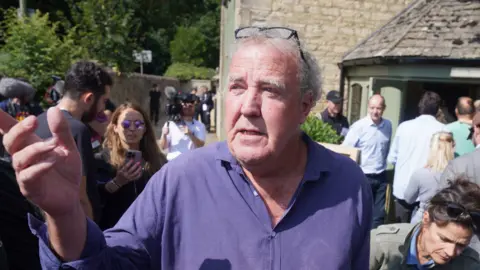 PA Media Jeremy Clarkson talking amongst a crowd of people outside his pub on his farm