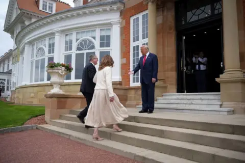 Getty Images PM Starmer and wife Victoria walk up steps of golf club where Trump greets them with hand outstretched