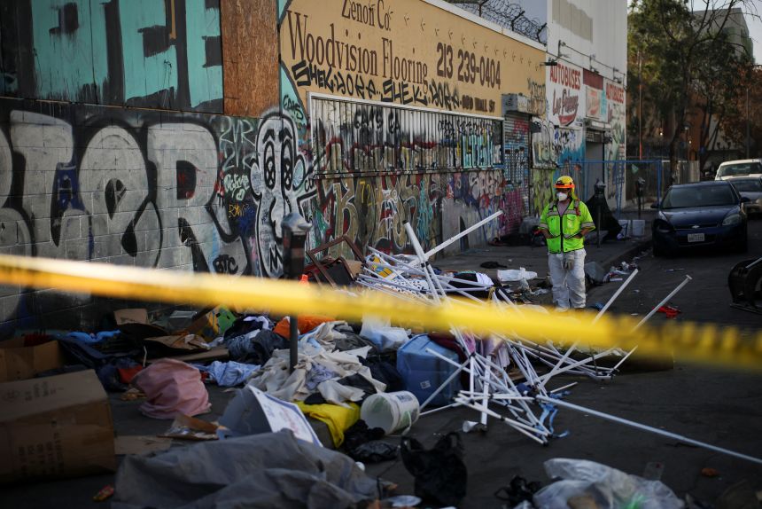 A worker stands on a corner during a street cleaning operation in Skid Row Los Angeles, California, U.S., December 9, 2024.