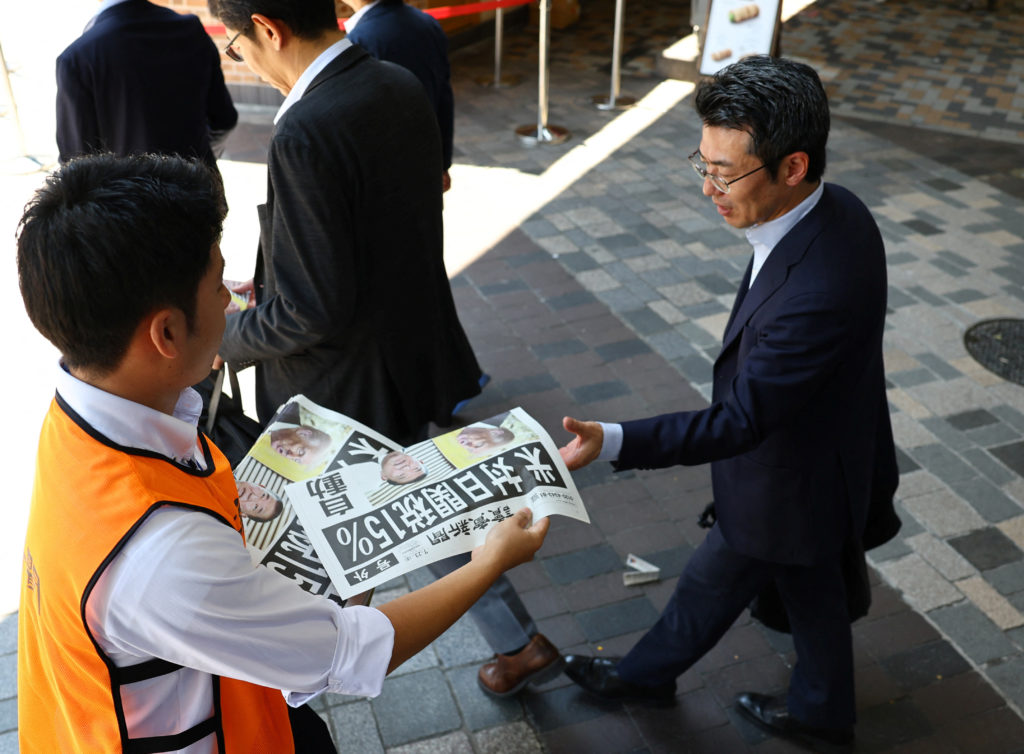 A staff from Yomiuri Shimbun newspaper distributes a special edition of the newspaper reporting the tariff deal agreement ...