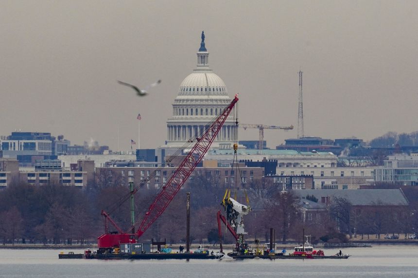 A crane retrieves part of the wreckage of American Airlines flight 5342 on February 3, 2025.