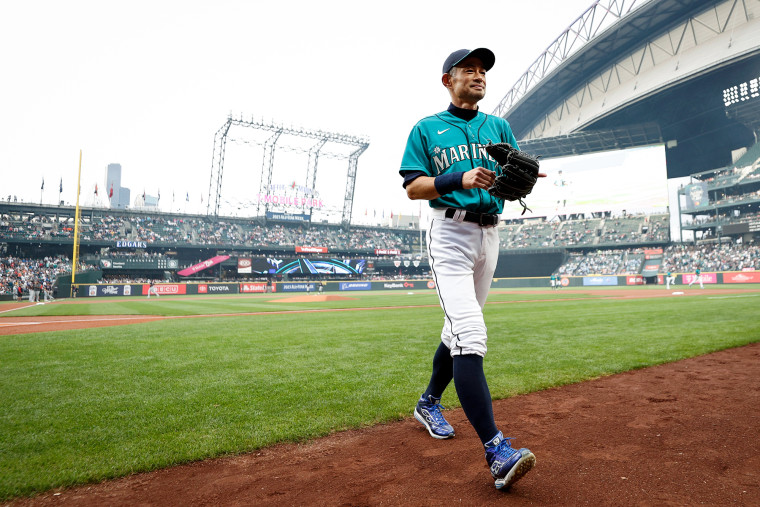 Ichiro Suzuki walks off of the baseball field in a Mariners uniform wearing a baseball glove