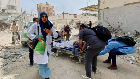 Reuters File photo showing Palestinians evacuating Kamal Adwan hospital in Beit Lahia, northern Gaza, during an Israeli offensive (21 May 2024)