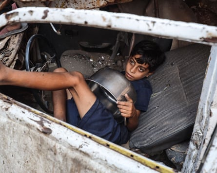 A Palestinian boy waits for hot food from a charity kitchen in Gaza City on Sunday. The World Food Programme says nearly one in three people in the territory do not eat for days at a stretch and thousands are 'on the verge of catastrophic hunger'.