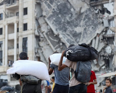 Palestinians carry aid supplies after trucks loaded with aid entered from Israel through central Gaza, in Gaza City on 22 July 2025.