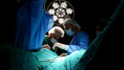 Reuters Medical personnel work in an operating room at Nasser hospital, in Khan Younis, southern Gaza, amid a critical fuel shortage (9 July 2025)