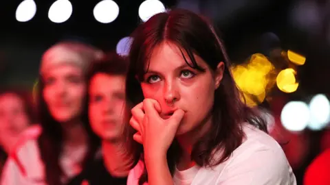 PA A young woman with shoulder length brown hair and a fringe bites her nails in Boxpark Croydon during the semi-final between England and Italy 