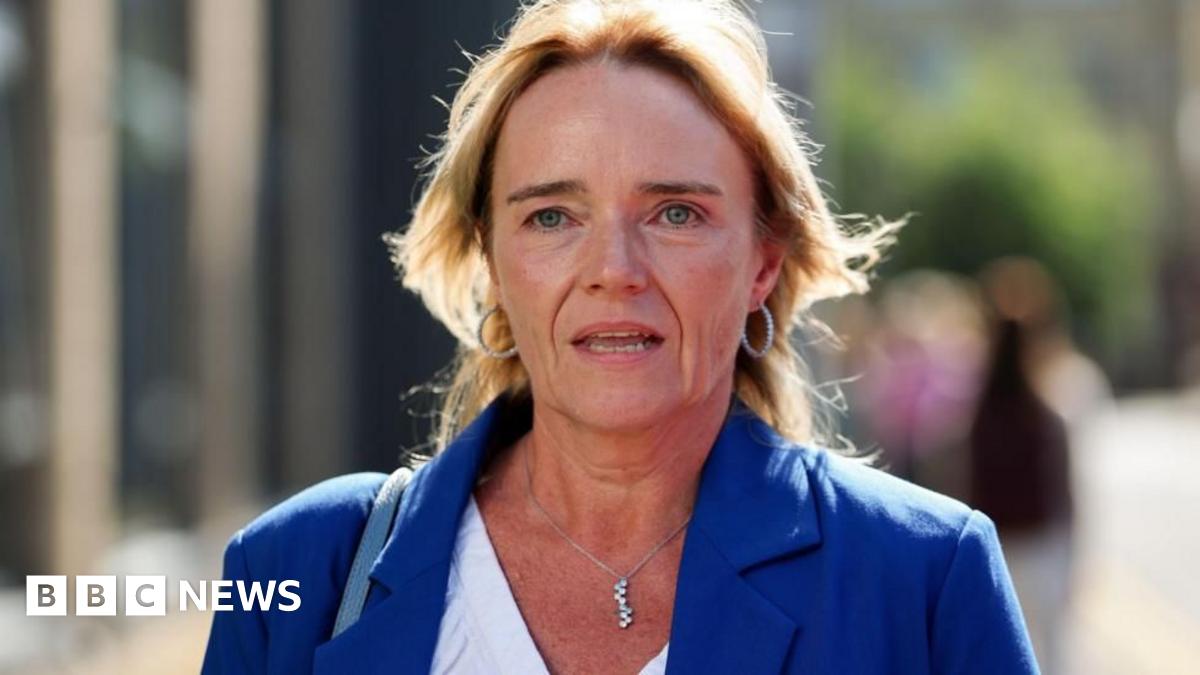 Sandie Peggie - a woman wearing a blue suit, with blond hair to her shoulders, walking outside