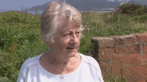 Margaret Barr looking slightly off camera. She has white hair and is wearing a white top.