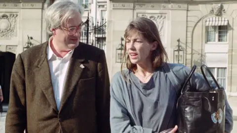 Getty Images Jane Birkin walking and talking with French director Bertrand Tavernier, with the bag under one arm
