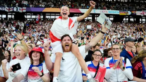 Nick Potts/PA wire A young girl draped in an England flag sits on a man's shoulder surrounded by cheering England fans in a packed stadium