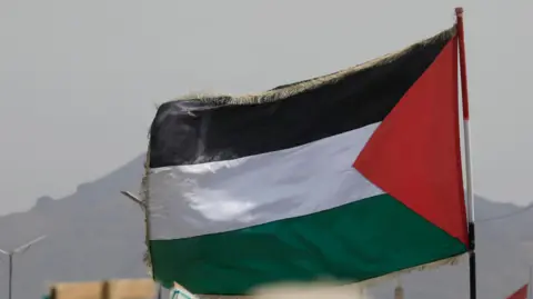 EPA A Palestinian flag flutters during a protest against the US and Israel, in Sana'a, Yemen.